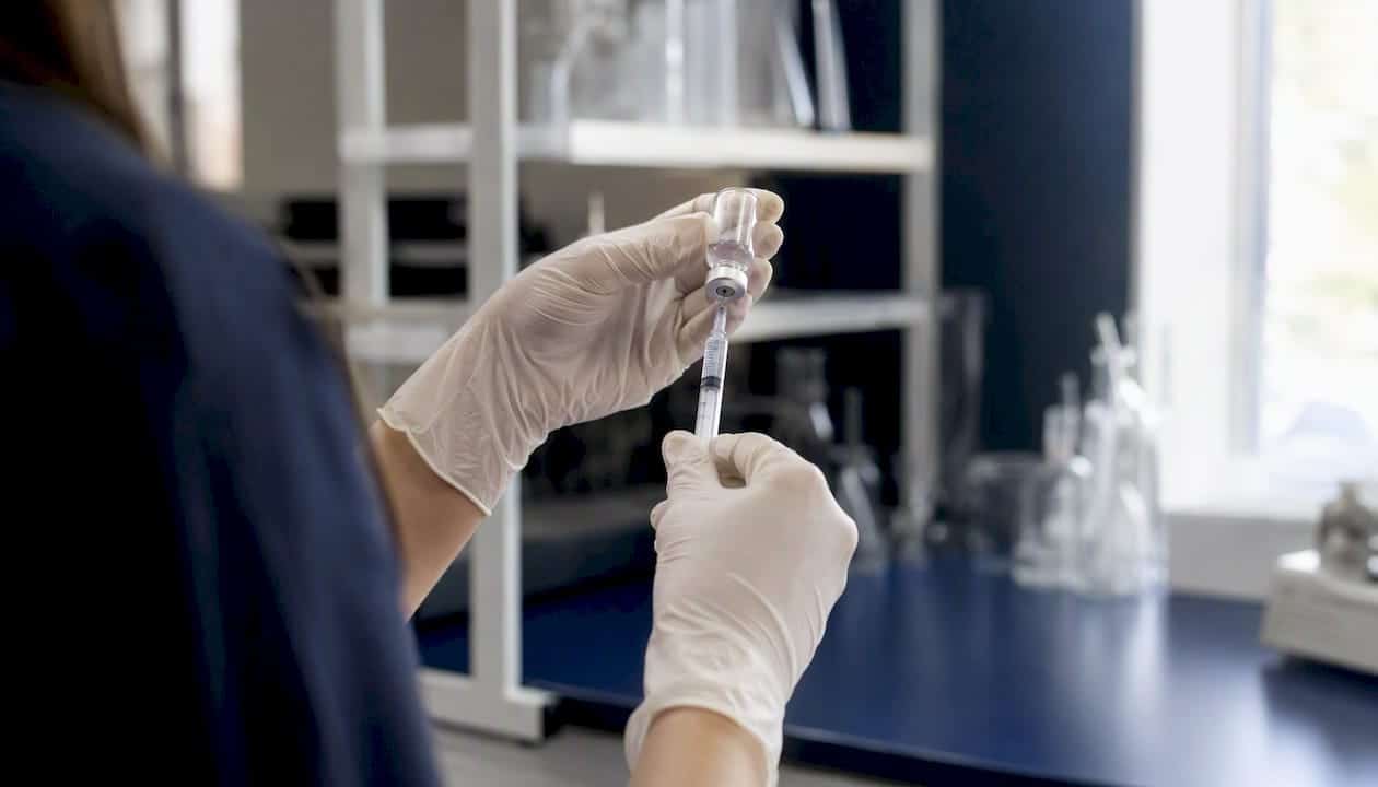 Hands drawing peptide from vial